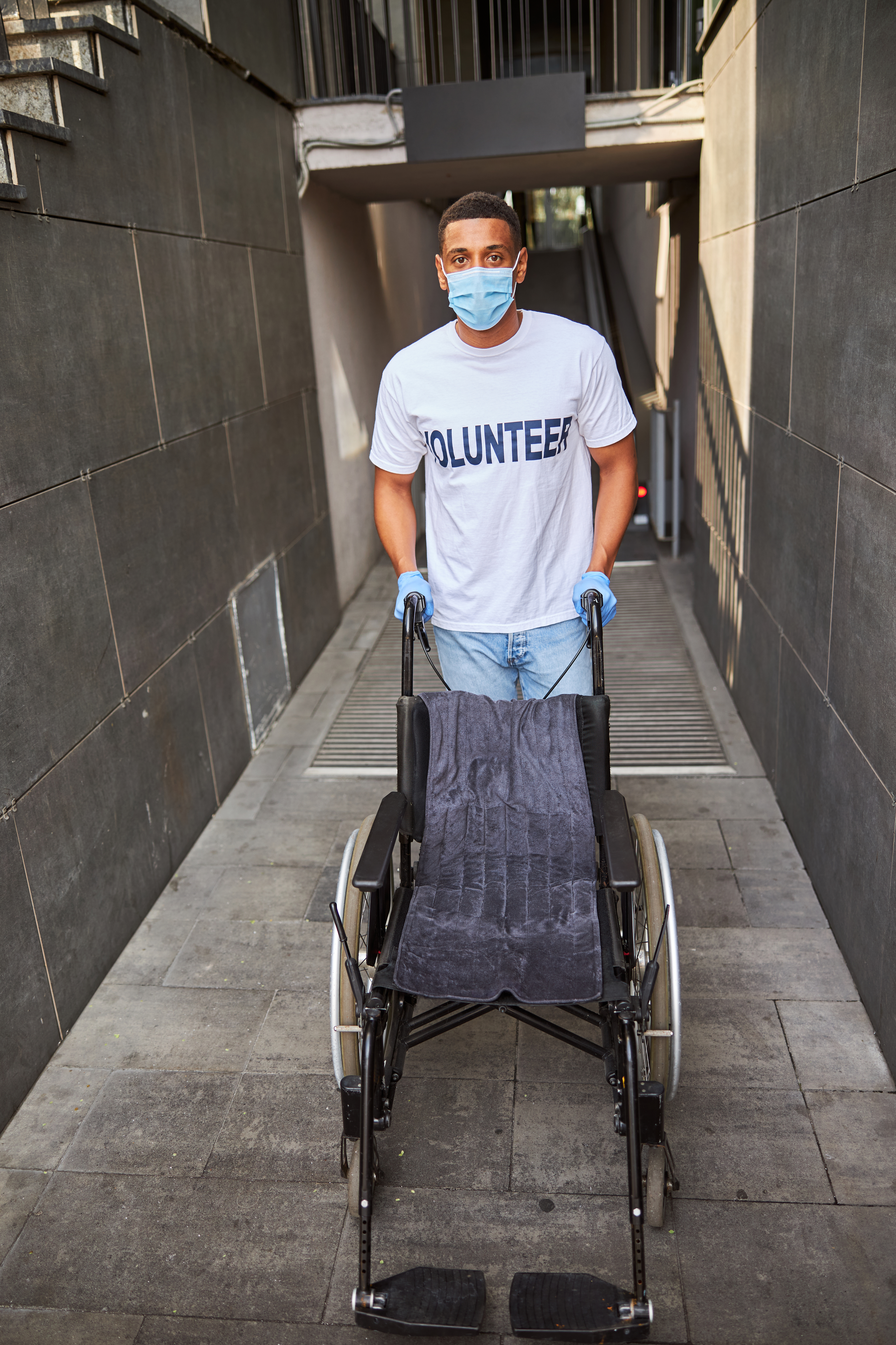 A cozy small bedroom in Auburn adult family homes features a single bed, nightstand, closed closet, wall-mounted TV, and a wooden dresser with a small plant.