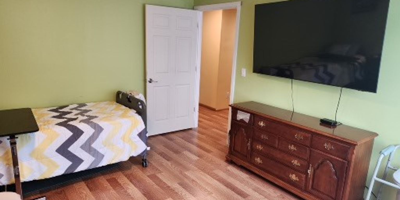 Three ripe raspberries hang from a branch with green leaves in front of a white wooden fence, capturing a tranquil moment reminiscent of peaceful gardens often enjoyed in senior care communities in Snohomish County.